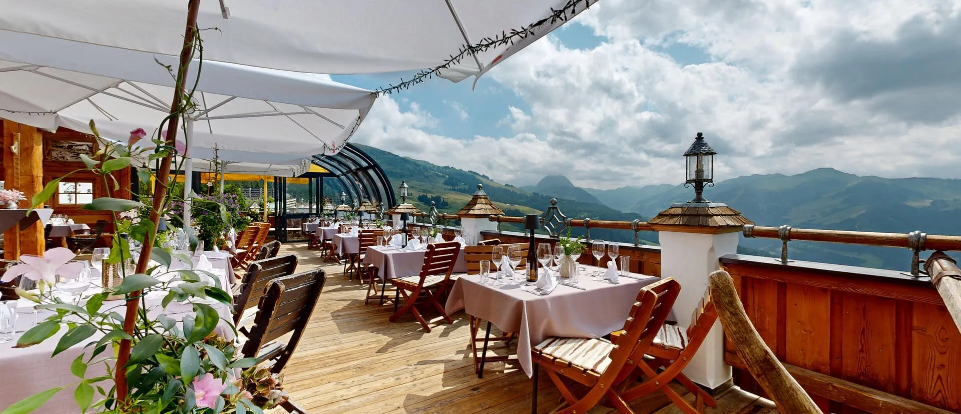 Gedeckte Tische auf der Sonnenterrasse der OchsAlm mit Panoramablick auf die Kitzbüheler Alpen