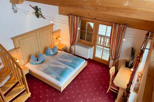 Schlafbereich der Suite Panorama mit Doppelbett, Schreibtisch und Balkon, von der Galerie aus gesehen