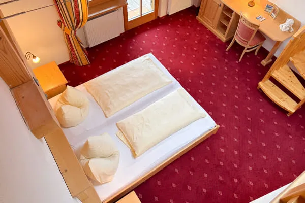 Blick von der Galerie auf den Schlafbereich der Suite Mountain mit Doppelbett und Balkonzugang