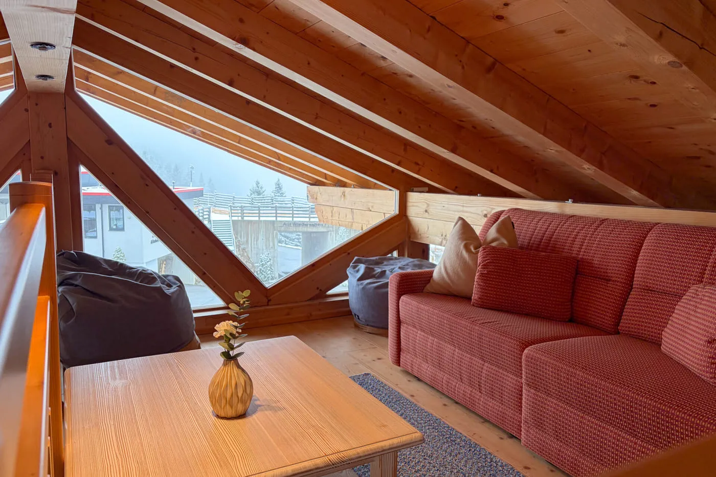 Gemütliche Sitzecke auf der Galerie der Suite Panorama mit Holzdecke und großem Panoramafenster