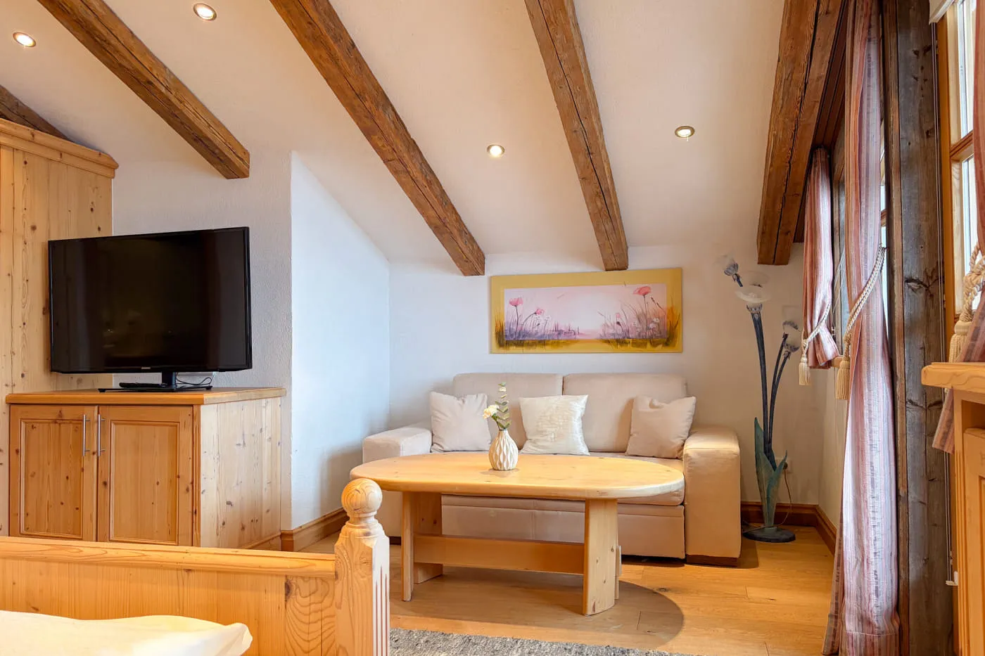 Wohnbereich der Suite Rettenstein mit gemütlicher Sitzecke, Altholzbalken und Zugang zum Balkon
